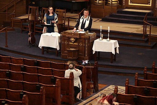 Rodef Shalom Rabbi Aaron Bisno, top center, delivers his sermon with soloist Molly May, left, and Rabbi Sharyn Henry in attendance, during an Erev Shabbot service that is being streamed live on Facebook, Friday, March 20, 2020. All events have been suspended at the synagogue until April 16, to help mitigate the spread of the COVID-19 virus. (AP Photo/Gene J. Puskar)