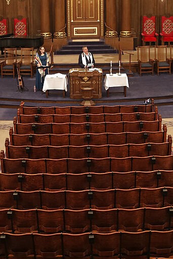 Rodef Shalom Rabbi Aaron Bisno, center, delivers his sermon with soloist Molly May, left, during an Erev Shabbot service that is being streamed live on Facebook, Friday, March 20, 2020. All events have been suspended at the synagogue until April 16, to help mitigate the spread of the COVID-19 virus. (AP Photo/Gene J. Puskar)