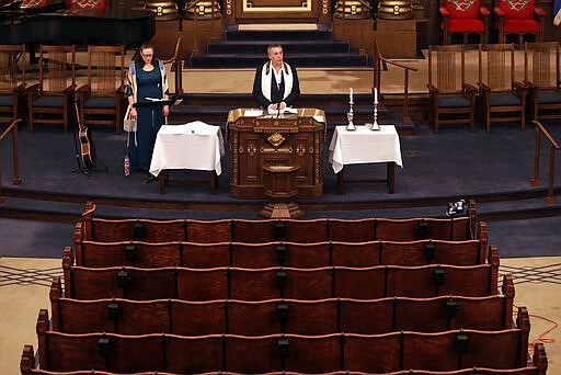 Rodef Shalom Rabbi Aaron Bisno, center, delivers his sermon with soloist Molly May, left, during an Erev Shabbot service that is being streamed live on Facebook, Friday, March 20, 2020. All events have been suspended at the synagogue until April 16, to help mitigate the spread of the COVID-19 virus. (AP Photo/Gene J. Puskar)