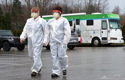 Registered nurse Stephanie Crilley, left, and nurse practitioner April Sweeney prepare to begin testing Friday, March 20, 2020, at the drive-through testing site at the AHN Health + Wellness Pavilion in Millcreek Township near Erie, Pa. Saint Vincent Hospital officials expected to test up to 40 patients daily at the site, which opened Friday. All patients tested must have a Saint Vincent Hospital physician referral and appointment. The samples will be tested for flu strains before they're tested for COVID-19. (Christopher Millette/Erie Times-News via AP)