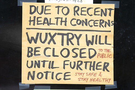 A sign in a record store window tells customers the store is closed to the public until further notice because of the coronavirus ,Friday, March 20, 2020, in Athens, Ga. (AP Photo/John Bazemore)