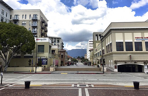 A pedestrian walks along a deserted upscale outdoor mall, The Paseo in Pasadena, Calif., Saturday, March 21, 2020. A little more than 24 hours after Gov. Gavin Newsom issued an unprecedented stay-at-home order to nearly 40 million residents to help curb the coronavirus spread, most Californians were faced with how to spend two days of free time with strict limits on their freedom. (AP Photo/John Antczak)