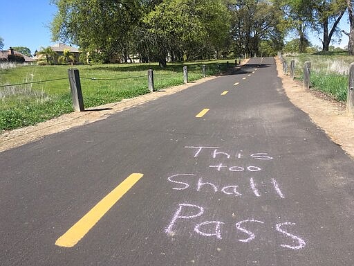 Chalked message on a bike trail in Roseville, Calif. on Saturday March 21, 2020. A little more than 24 hours after Gov. Gavin Newsom issued an unprecedented stay-at-home order to nearly 40 million residents to help curb the coronavirus spread, most Californians were faced with how to spend two days of free time with strict limits on their freedom. (AP Photo/Don Thompson)