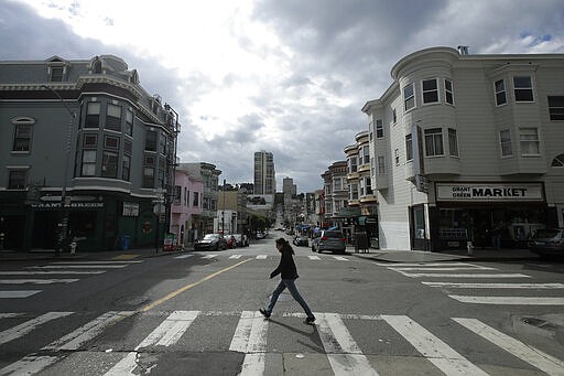 A man walks alone while crossing Green Street in the North Beach neighborhood of San Francisco, Saturday, March 21, 2020. Some 40 million Californians are coping with their first weekend under a statewide order requiring them to stay at home to help curb the spread of the coronavirus.(AP Photo/Jeff Chiu)