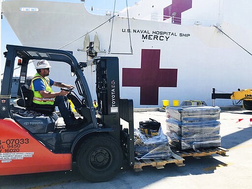 Steve King, a Naval Facilities Engineering Command Southwest forklift driver, prepares to deliver pallets during a supply load aboard the Military Sealift Command hospital ship USNS Mercy (T-AH 19) at Naval Base San Diego, adjacent to San Diego, Calif., Saturday, March 21, 2020. Mercy is preparing to deploy in support of the nation's COVID-19 response efforts and will serve as a referral hospital for non-COVID-19 patients currently admitted to shore-based hospitals. (Senior Chief Mass Communication Specialist Mike Jones/U.S. Navy via AP)