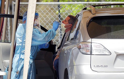 A medical worker tests a person for the coronavirus at a drive-through facility primarily for first responders and medical personnel in San Antonio, Tuesday, March 17, 2020. Texas Gov. Greg Abbott said, &quot;This is not a time to panic. It's not as if we have never been through this before. We've been through this many, many times.&quot; (AP Photo/Eric Gay)