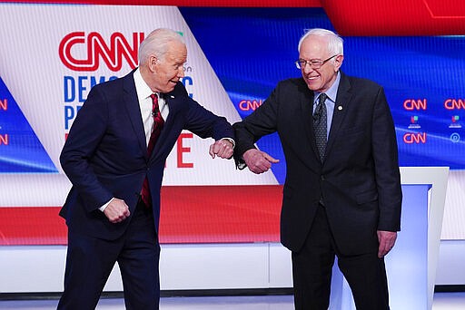 Former Vice President Joe Biden, left, and Sen. Bernie Sanders, I-Vt., right, greet one another before they participate in a Democratic presidential primary debate at CNN Studios in Washington, Sunday, March 15, 2020. (AP Photo/Evan Vucci)