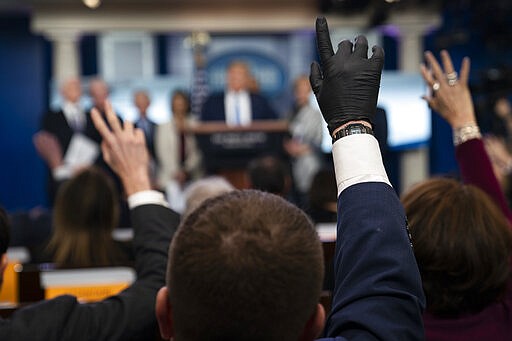 Reporters raise their hands to ask President Donald Trump questions during a press briefing with the coronavirus task force, at the White House, Monday, March 16, 2020, in Washington. (AP Photo/Evan Vucci)