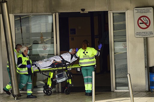 Ambulances medical staff deliver a patient wearing protection masks at Cruces hospital, in Bilbao, northern Spain, Saturday, March 21, 2020. For some people the COVID-19 coronavirus causes mild or moderate symptoms, but for some it causes severe illness. (AP Photo/Alvaro Barrientos)