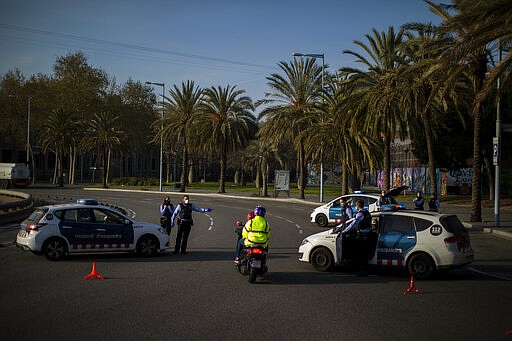 Catalan police officers wearing facemarks stop two men on a motorcycle at a checkpoint as authorities control public movements in Barcelona, Spain, Saturday, March 21, 2020. For some people the COVID-19 coronavirus causes mild or moderate symptoms, but for some it causes severe illness. (AP Photo/Emilio Morenatti)