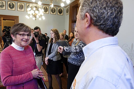 Kansas Gov. Laura Kelly, left, talks to Chuck Magerl, right, the owner of the Free State Brewing Company pub in Lawrence, Kan,, after a news conference to announce the launch of a new state loan program, Friday, March 20, 2020, at the Statehouse in Topeka, Kan. The new program will make $5 million in short-term, no-interest loans to bars, taverns, restaurants and motels struggling to cover their operating expenses. (AP Photo/John Hanna)