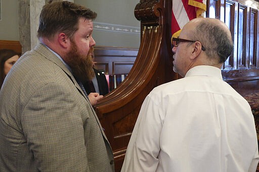 In this photo from Thursday, March 19, 2020, Kansas House Speaker Blaine Finch, left, R-Ottawa, confers with House Minority Leader Tom Sawyer, right, D-Wichita, as the House prepares to adjourn at the Statehouse in Topeka, Kan. Finch says the widespread nature of the coronavirus pandemic has lawmakers wanting to re-examine the governor's power in disasters. (AP Photo/John Hanna)