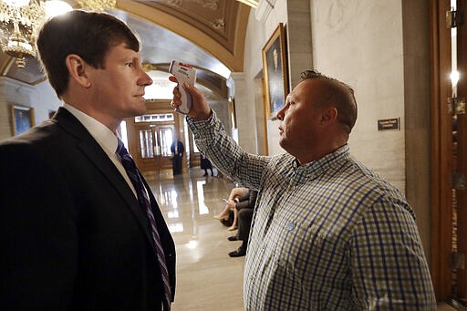 FILE - In this Monday, March 16, 2020 file photo, Sen. Brian Kelsey, R-Germantown, left, has his temperature taken by Scott Wyatt, of the Tennessee Department of Health, before Kelsey entered a room for a news conference concerning the state's response to the COVID-19 coronavirus in Nashville, Tenn. (AP Photo/Mark Humphrey)