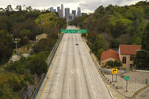 FILE - In this March 20, 2020 file photo Extremely light traffic moves along the 110 Harbor Freeway toward downtown mid afternoon  in Los Angeles.  Reaction to the coronavirus, change came to the United States during the third week of March in 2020. It did not come immediately, though it came quite quickly. There was no explosion, no invasion other than a microscopic one that nobody could see.  (AP Photo/Mark J. Terrill, File)