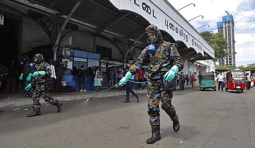 Sri Lankan government soldiers in protective clothes spray disinfectants at a railway station in Colombo, Sri Lanka, Wednesday, March 18, 2020. For most people, the new coronavirus causes only mild or moderate symptoms. For some, it can cause more severe illness, especially in older adults and people with existing health problems. (AP Photo/Eranga Jayawardena)