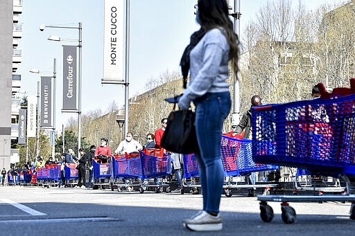 People queue waiting to enter a supermarket in Turin, Italy, Saturday, March 21, 2020. For most people, the new coronavirus causes only mild or moderate symptoms. For some it can cause more severe illness. (Marco Alpozzi/LaPresse via AP)