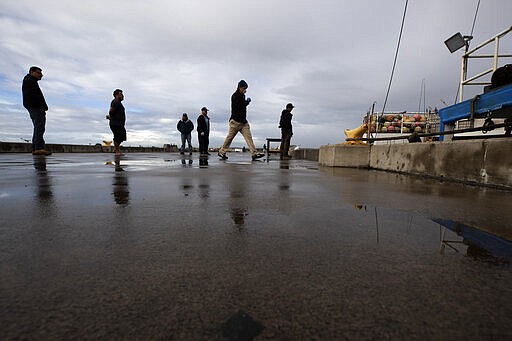 People keep their distance as they wait in line to buy fish from boat captain Nick Haworth, second from right, Friday, March 20, 2020, in San Diego. Haworth came home to California after weeks at sea to find a state all but shuttered due to coronavirus measures, and nowhere to sell their catch. A handful of tuna boats filled with tens of thousands of pounds of fish are now floating off San Diego's coast as they scramble to find customers. Haworth was selling on Friday to individuals for less than half what he would get from wholesalers. &quot;This is a quarantine special,&quot; he joked. (AP Photo/Gregory Bull)