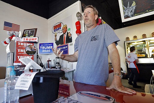 In this Wednesday, March 18, 2020, photo, Cliff Gephart, owner of Conservative Grounds coffee shop in Largo, Fla., speaks to a journalist at his shop. The shop features President Donald Trump memorabilia, including a replica of the Oval Office. (AP Photo/Chris O'Meara)