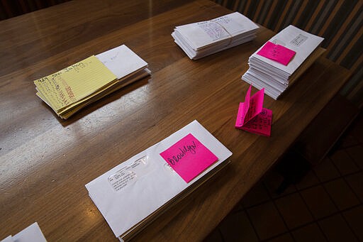 Paychecks are stacked on a table at Junior's Restaurant for distribution to employees, Thursday, March 19, 2020 in the Brooklyn borough of New York. The company has closed its four locations due to the coronavirus and is laying off 650 of 850 employees. (AP Photo/Mark Lennihan)