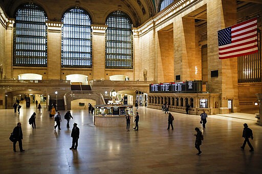 FILE - In this March 20, 2020, file photo a MTA conductor stands in a beam of light at Grand Center Terminal that is sparsely populated during rush hour due to COVID-19 concerns in New York. America has a history of unifying in trying times and rallying around the president, at least temporarily, in a crisis. But after years of division, there's little sign the coronavirus has punctured the nation&#146;s partisan bubbles. (AP Photo/John Minchillo, File)