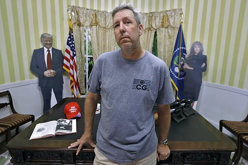 In this Wednesday, March 18, 2020, photo, Cliff Gephart, owner of Conservative Grounds coffee shop, in Largo, Fla., poses for a photo at the shop, which features President Donald Trump memorabilia, including a replica of the Oval Office. (AP Photo/Chris O'Meara)