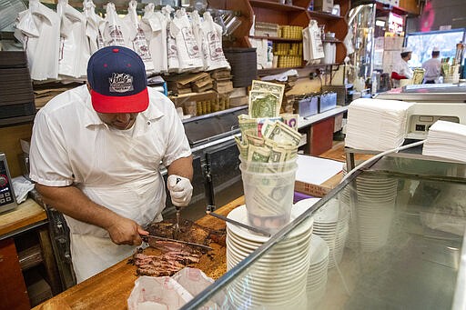 In this March 19, 2020 photo, a cutter slices meet for a to go order at Katz's Delicatessen on the Lower East Side of New York. The iconic eatery is only open for take out and delivery orders due to the coronavirus outbreak. (AP Photo/Mary Altaffer)