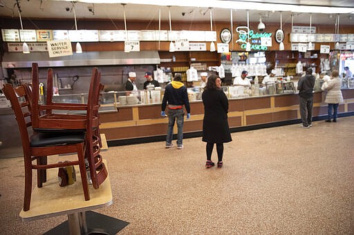 I this March 19, 2020 photo, chairs are stacked on the table where the Meg Ryan and Billy Crystal filmed the famous scene from the movie &quot;When Harry Met Sally,&quot; as customers wait for take out orders at Katz's Delicatessen on the Lower East Side of New York. The iconic eatery is only open for take out and delivery orders due to the coronavirus outbreak. (AP Photo/Mary Altaffer)