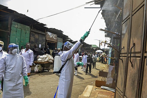 Kenyan Health Ministry officials spray disinfectant onto the steel door of a street stall to control the spread of the new coronavirus, in the Gikomba outdoor street market in the capital Nairobi, Kenya Saturday, March 21, 2020. For most people, the new coronavirus causes only mild or moderate symptoms such as fever and cough and the vast majority recover in 2-6 weeks but for some, especially older adults and people with existing health issues, the virus that causes COVID-19 can result in more severe illness, including pneumonia. (AP Photo/John Muchucha)