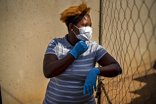 Mabatho Mphuthi is one of the very few people wearing a mask in response to the COVID-19 virus outbreak in the Diepsloot township north of Johannesburg, South Africa, Saturday March 21, 2020.  For most people the virus causes only mild or moderate symptoms. For others it can cause more severe illness, especially in older adults and people with existing health problems. (AP Photo/Jerome Delay)