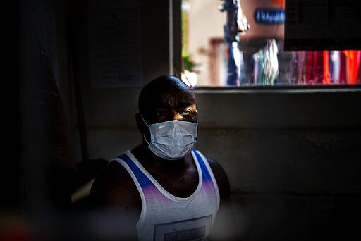 Prince, a Nigerian money changer, is one of the very few people wearing a mask in response to the COVID-19 virus outbreak in the Diepsloot township north of Johannesburg, South Africa, Saturday March 21, 2020.  For most people the virus causes only mild or moderate symptoms. For others it can cause more severe illness, especially in older adults and people with existing health problems. (AP Photo/Jerome Delay)