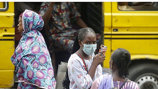 A woman wearing a face mask walks nearby the Central Mosque in Lagos, Nigeria, Friday, March 20, 2020. The government banned all religious activities for four weeks following confirmation of coronavirus cases in the country.  (AP Photo/Sunday Alamba)