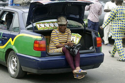 A woman sells herbal medicine from the back of a car, outside the Central Mosque in Lagos, Nigeria, Friday, March 20, 2020. The government banned all religious activities for four weeks following confirmation of coronavirus cases in the country. (AP Photo/ Sunday Alamba)