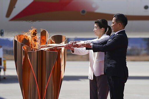 Three-time Olympic gold medalists Tadahiro Nomura, right, and Saori Yoshida light the torch during Olympic Flame Arrival Ceremony at Japan Air Self-Defense Force Matsushima Base in Higashimatsushima in Miyagi Prefecture, north of Tokyo, Friday, March 20, 2020. The Olympic flame from Greece arrived in Japan even as the opening of the the Tokyo Games in four months is in doubt with more voices suggesting the games should to be postponed or canceled because of the worldwide virus pandemic. (AP Photo/Eugene Hoshiko)