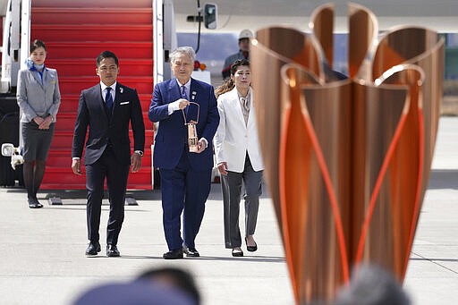 Tokyo 2020 Olympics chief Yoshiro Mori, center, followed by three-time Olympic gold medalists Tadahiro Nomura and Saori Yoshida, right, carries the Olympic flame during the Flame Arrival Ceremony at Japan Air Self-Defense Force Matsushima Base in Higashimatsushima in Miyagi Prefecture, north of Tokyo, Friday, March 20, 2020. The Olympic flame from Greece arrived in Japan even as the opening of the the Tokyo Games in four months is in doubt with more voices suggesting the games should to be postponed or canceled because of the worldwide virus pandemic. (AP Photo/Eugene Hoshiko)