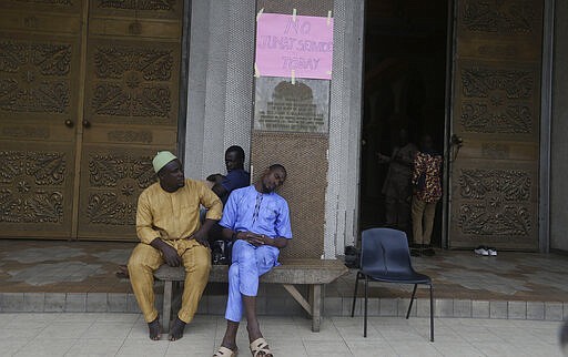 A Muslim man sleeps outside the central mosque in Lagos, Nigeria, Friday, March 20, 2020. The government banned all religious activities for four weeks following confirmation of coronavirus cases in the country. (AP Photo/Sunday Alamba)