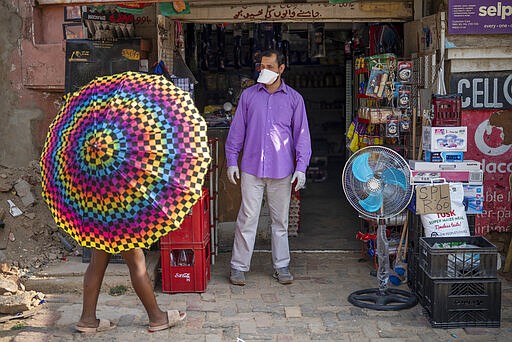 Iftikhar Ahmad, a Pakistani shopkeeper, is one of the very few wearing a mask in the Diepsloot township north of Johannesburg, South Africa, Saturday March 21, 2020.   For most people the virus causes only mild or moderate symptoms. For others it can cause more severe illness, especially in older adults and people with existing health problems. (AP Photo/Jerome Delay)