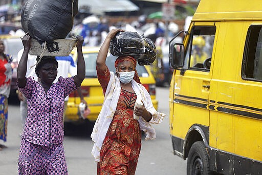 A woman wearing a face mask walks on the street, opposite the Central mosque in Lagos, Nigeria, Friday, March 20, 2020. The government banned all religious activities for four weeks following confirmation of coronavirus cases in the country. (AP Photo/ Sunday Alamba)