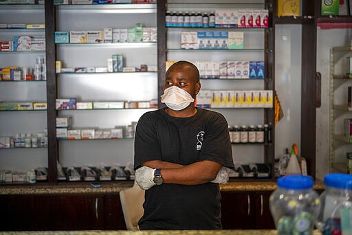 Thabo Rakgotho, a pharmacist, waits for customers in the Diepsloot township north of Johannesburg, South Africa, Saturday March 21, 2020.  For most people the virus causes only mild or moderate symptoms. For others it can cause more severe illness, especially in older adults and people with existing health problems. (AP Photo/Jerome Delay)