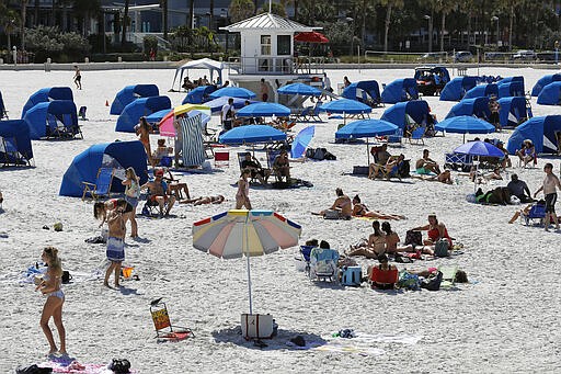 FILE - In this March 18, 2020, file photo visitors enjoy Clearwater Beach  in Clearwater Beach, Fla. Beach goers are keeping a safe distance from each other to help protect from the spread of the coronavirus. America has a history of unifying in trying times and rallying around the president, at least temporarily, in a crisis. But after years of division, there's little sign the coronavirus has punctured the nation&#146;s partisan bubbles. (AP Photo/Chris O'Meara, File)