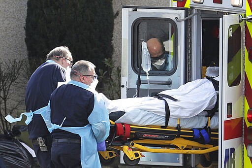 A person is loaded into an ambulance, Thursday, March 12, 2020, at the Life Care Center in Kirkland, Wash., near Seattle. The nursing home is at the center of the outbreak of the COVID-19 coronavirus in Washington state. For most people, the new coronavirus causes only mild or moderate symptoms. For some it can cause more severe illness, especially in older adults and people with existing health problems. (AP Photo/Ted S. Warren)