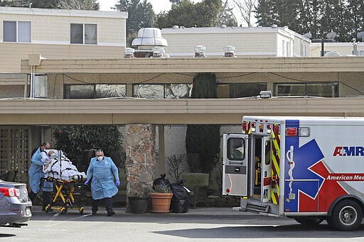 In this March 12, 2020, photo, a person is loaded into an ambulance at Life Care Center in Kirkland, Wash., which has been at the center of the COVID-19 coronavirus outbreak in the state. Residents of assisted living facilities and their loved ones are facing a grim situation as the coronavirus spreads across the country, placing elderly people especially at risk. (AP Photo/Ted S. Warren)
