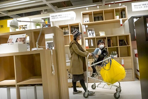 A woman and child wear face masks to protect against coronavirus infection as they shop at an IKEA store in Beijing, Saturday, March 21, 2020. Three major American states are locking down their residents in the face of a rapidly advancing virus storm that is already severely straining health systems in parts of Europe. The virus causes only mild or moderate symptoms, such as fever and cough, for most people, but severe illness is more likely in the elderly and people with existing health problems. (AP Photo/Mark Schiefelbein)