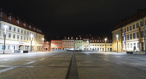 The deserted Maximiliansplatz is seen in the city center of Bamberg, Germany, shortly after midnight, early Saturday morning, March 21, 2020. A curfew went into effect for Bavaria. Leaving one's own home is now only allowed if there are good reasons. (Nicolas Armer/dpa via AP)