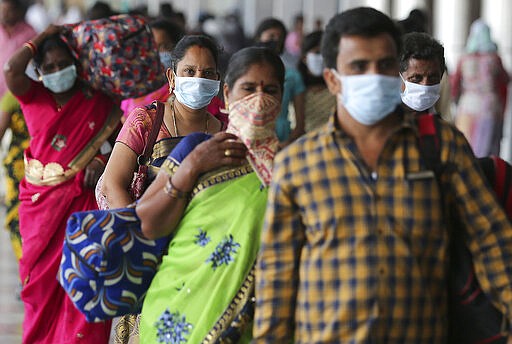 Indian passengers wear face masks as a precaution against COVID-19 arrive at Secunderabad Railway Station in Hyderabad, India, Saturday, March 21, 2020. For most people, the new coronavirus causes only mild or moderate symptoms. For some it can cause more severe illness. (AP Photo/Mahesh Kumar A.)