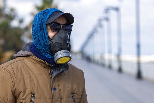 A man wears a tear gas mask to help protect himself from the new coronavirus as he walks at Beirut's seaside corniche, or waterfront promenade, along the Mediterranean Sea, which is almost empty of residents and tourists in Beirut, Lebanon, Saturday, March 21, 2020. For most people, the new coronavirus causes only mild or moderate symptoms, such as fever and cough. For some, especially older adults and people with existing health problems, it can cause more severe illness, including pneumonia. (AP Photo/Hassan Ammar)