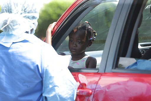 A child who has a high temperature has her details recorded by a health worker at a public hospital, in Harare, Zimbabwe, Saturday, March 21, 2020. Zimbabwean President Emmerson Mnangagwa announced a national disaster even before his country confirmed its first virus case on Friday. On Saturday, his country announced the first case in the capital, Harare. (AP Photo/Tsvangirayi Mukwazhi)