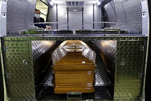 Roberto Cusimano, owner of San Giuseppe funeral home, left, is flanked by an employee as they prepare documents for transportation of the coffin of Concetta, 73 years old, who died with Coronavirus, at the Multimedica hospital morgue, in Milan, Italy, Saturday, March 21, 2020. The coffin will be carried to the cemetery of Caravaggio. For most people, the new coronavirus causes only mild or moderate symptoms. For some it can cause more severe illness. (AP Photo/Luca Bruno)