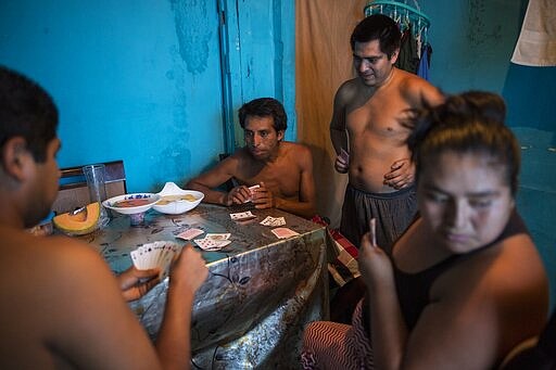 Members of the Cucchi family play cards inside their house in Lima, Peru, Saturday, March 21, 2020. Peru is in its six day of a government decreed state of emergency amid the presence of COVID-19. (AP Photo/Rodrigo Abd)