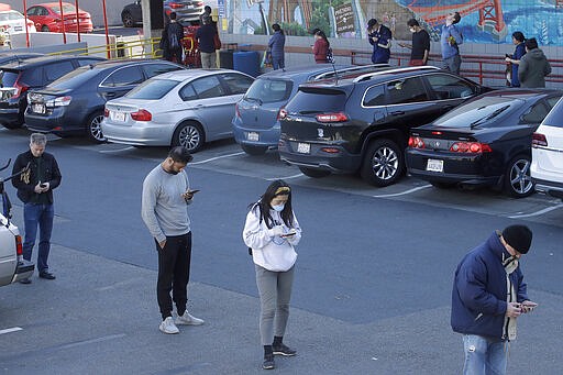 People keep their distance from each other while waiting in line to enter a Trader Joe's grocery store in San Francisco, Saturday, March 21, 2020. (AP Photo/Jeff Chiu)