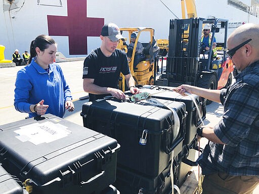 Master-at-Arms 3rd Class Ashlee McCasland, Master-at-Arms 2nd Class Jonathan Shaw and Senior Chief Master-at-Arms Lou Canton prepare pallets of supplies to be loaded aboard the Military Sealift Command hospital ship USNS Mercy (T-AH 19) at Naval Base San Diego, adjacent to San Diego, Calif., Saturday, March 21, 2020. Mercy is preparing to deploy in support of the nation's COVID-19 response efforts and will serve as a referral hospital for non-COVID-19 patients currently admitted to shore-based hospitals. (Senior Chief Mass Communication Specialist Mike Jones/U.S. Navy via AP)